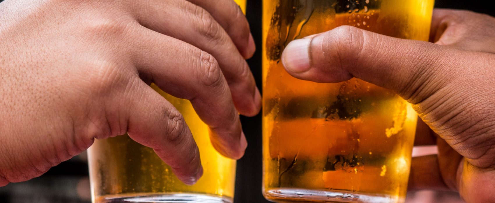 Two beer glasses being held up in the air